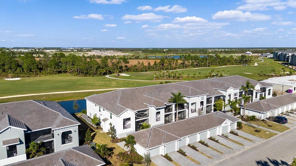 An aerial view shows a multi-unit residential building with attached garages next to a golf course — 12390 WELLEN GOLF STREET UNIT 201, VENICE, FL