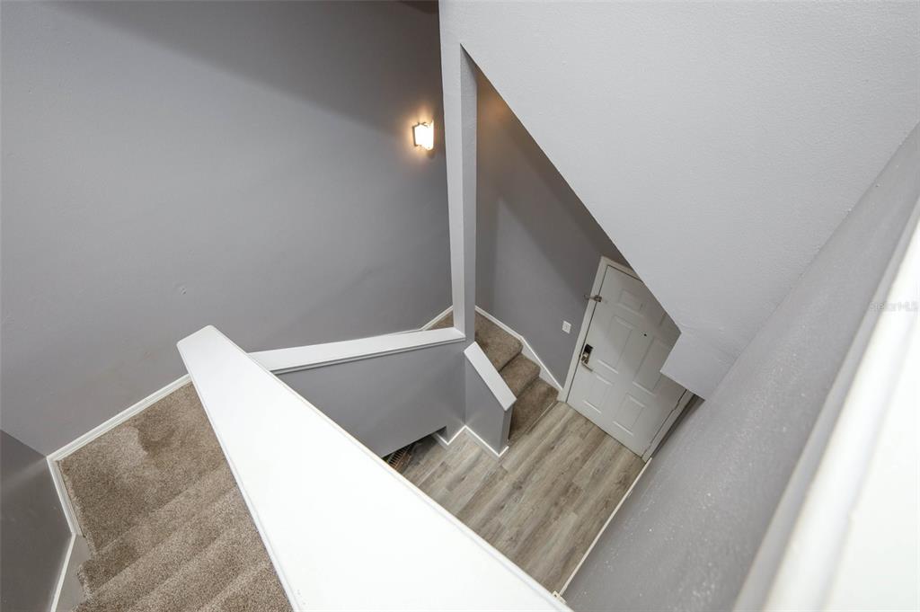 A high-angle view shows a carpeted staircase leading down to a wood-floored entryway — 6070 WESTGATE DRIVE UNIT 204, ORLANDO, FL