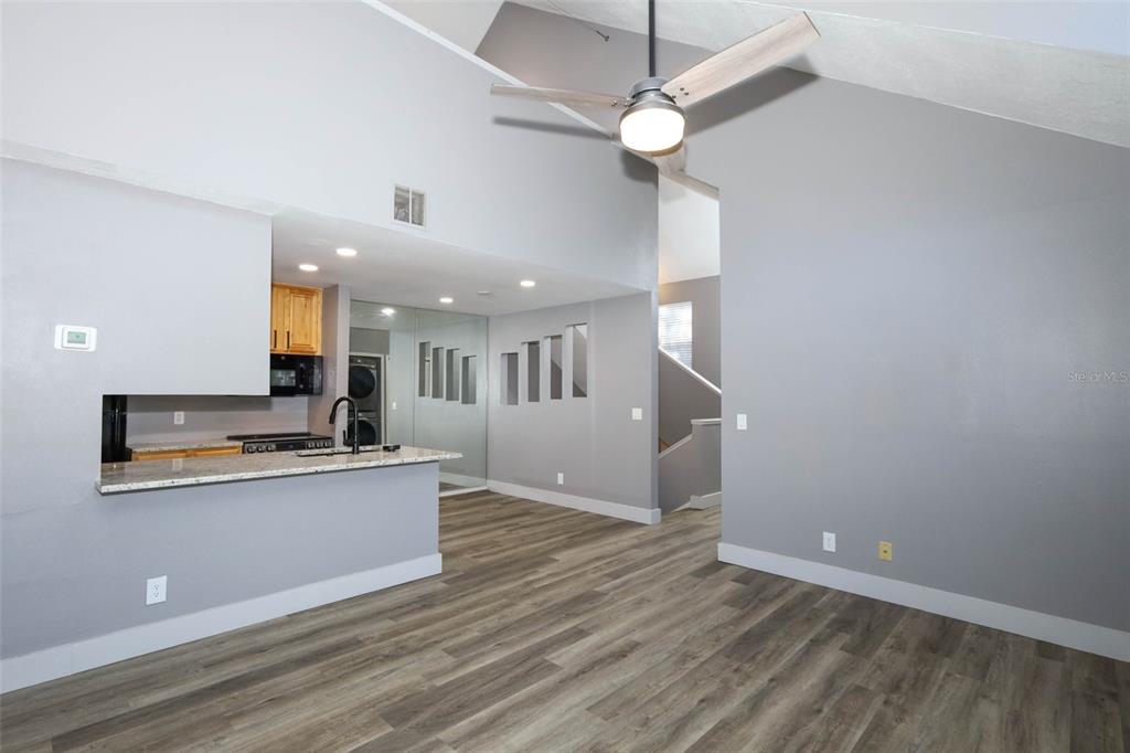 A living area with gray walls, wood-look flooring, a ceiling fan, and an open kitchen — 6070 WESTGATE DRIVE UNIT 204, ORLANDO, FL