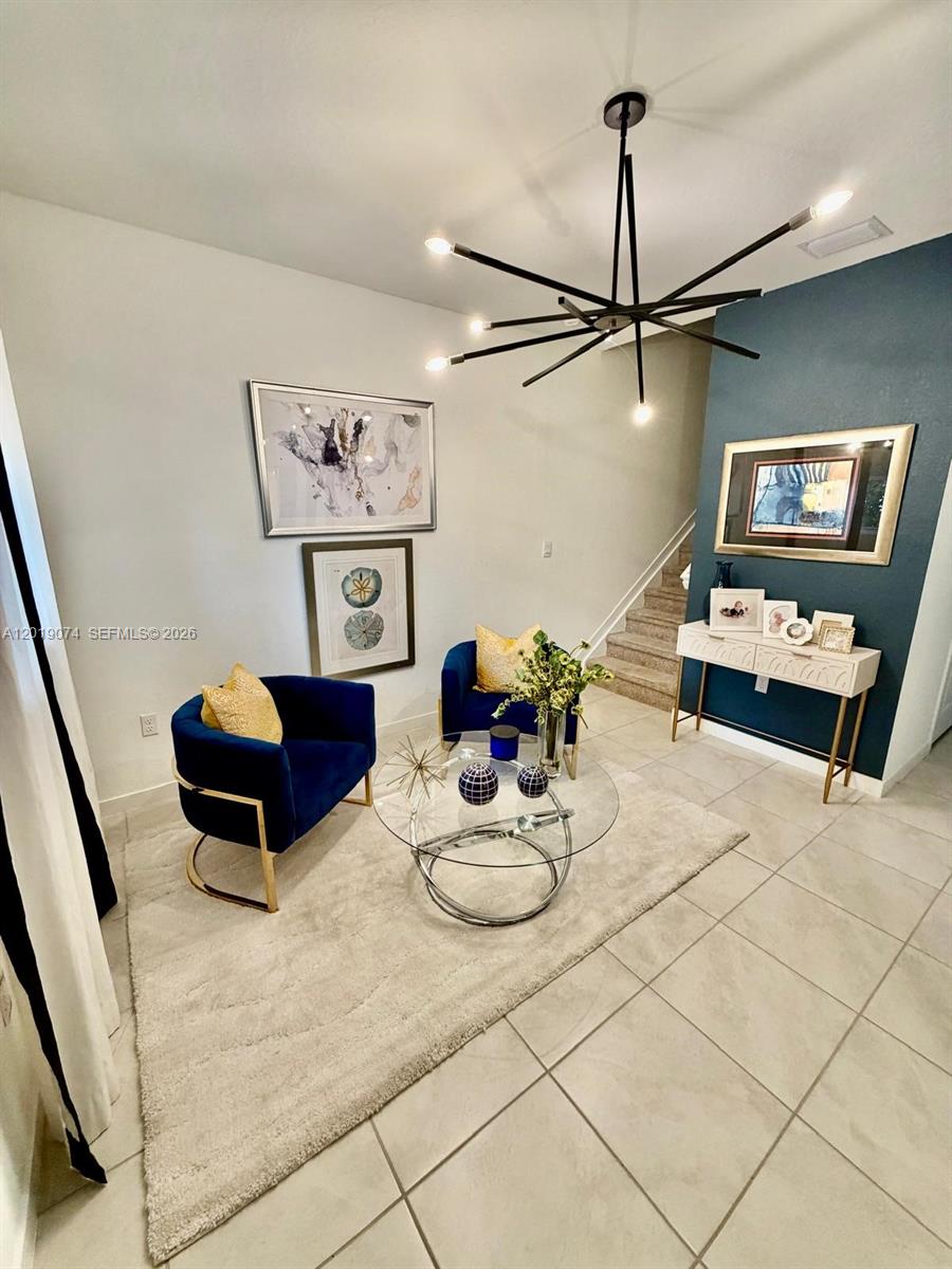 A modern sitting area features two blue velvet chairs, a glass coffee table, and chandelier — 1710 SE 9th Ave, Homestead FL 33034, HOMESTEAD, FL