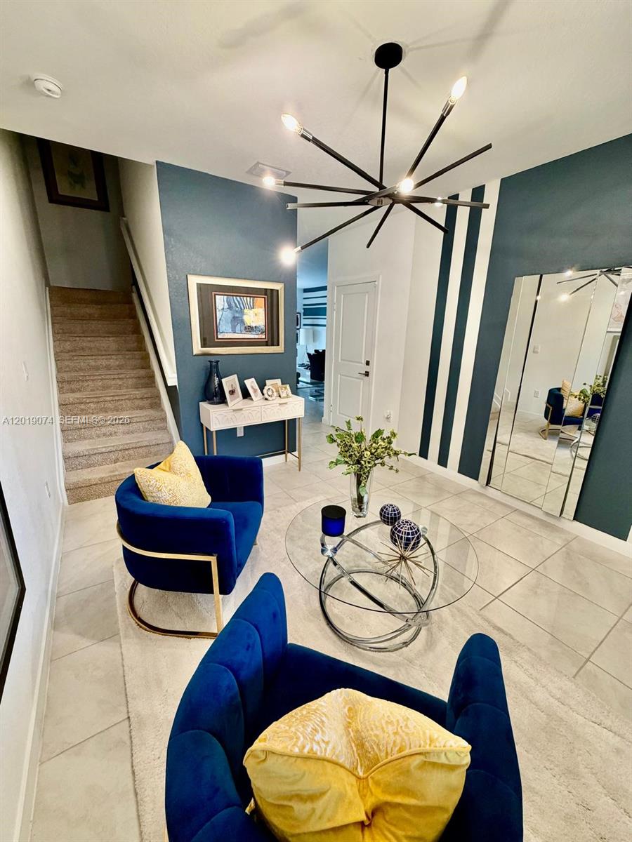 A modern entryway features blue velvet chairs, a glass coffee table, and a geometric chandelier — 1710 SE 9th Ave, Homestead FL 33034, HOMESTEAD, FL