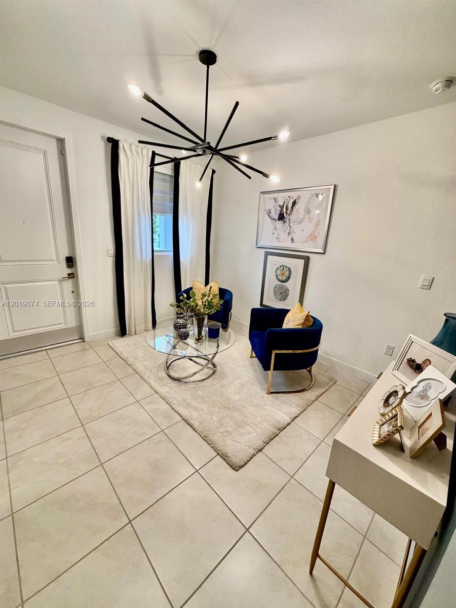 A small sitting area features two blue armchairs, a glass coffee table, and tile flooring — 1710 SE 9th Ave, Homestead FL 33034, HOMESTEAD, FL