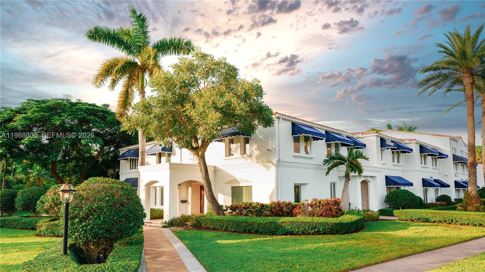 A white two-story building with blue awnings stands behind a manicured lawn and palm trees — 2525 Indian Mound Trl, Coral Gables FL 33134, CORAL GABLES, FL