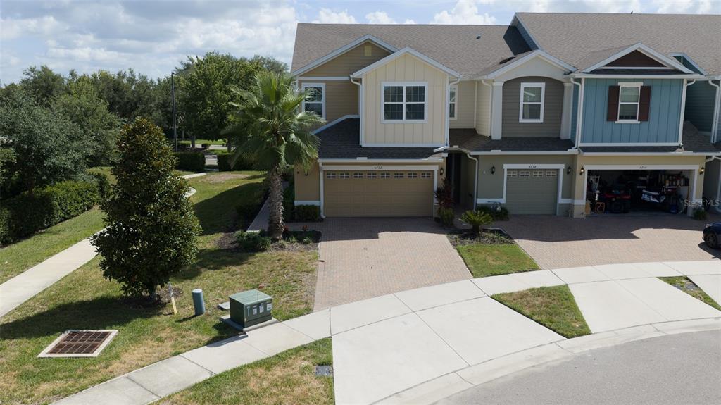 An exterior view of a multi-story townhouse with a paved driveway and a palm tree — 5732 SPOTTED HARRIER WAY, LITHIA, FL