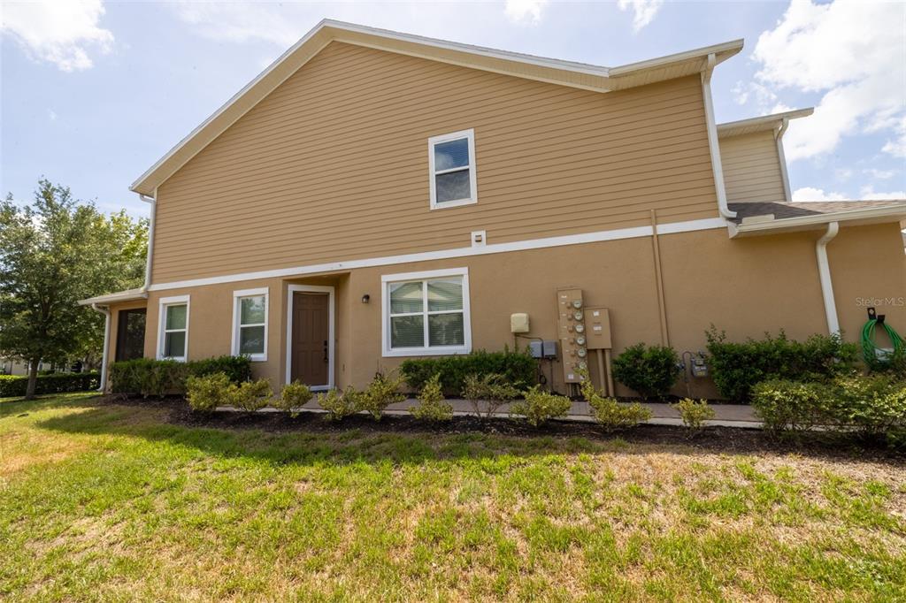 The exterior of a two-story house features tan siding, stucco walls, and a brown door — 5732 SPOTTED HARRIER WAY, LITHIA, FL