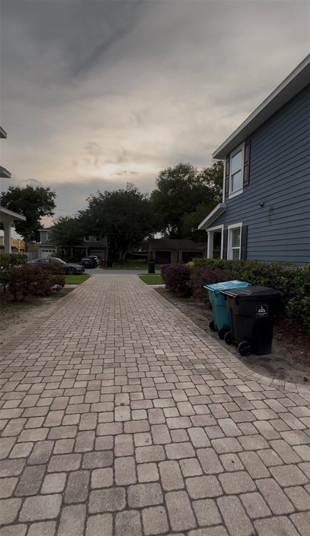 A paved driveway leads toward a house with blue siding and two trash bins — 2607 S BROWN AVENUE, ORLANDO, FL