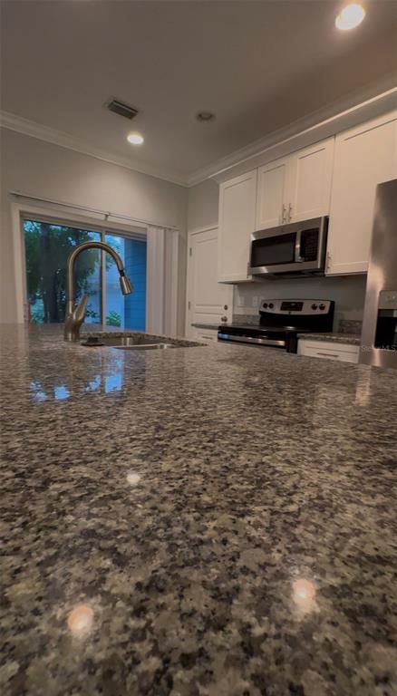 A kitchen features a large granite island, white cabinets, stainless steel appliances, and a sliding door — 2607 S BROWN AVENUE, ORLANDO, FL