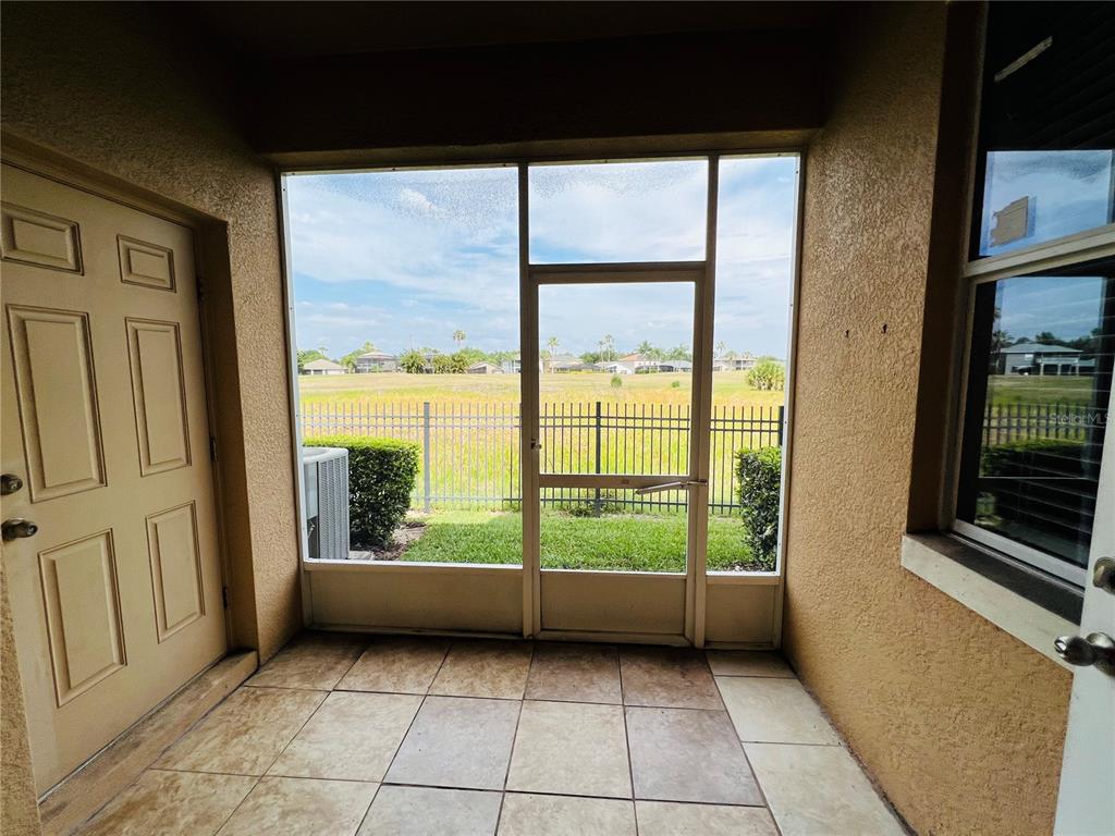 A tiled patio features a screen door leading to a fenced backyard with a grassy field — 1241 PRIORY CIRCLE, WINTER GARDEN, FL