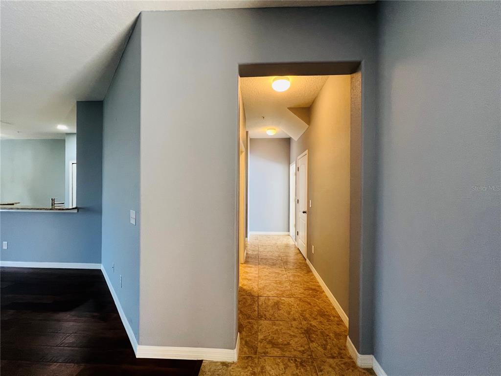 A hallway with tiled flooring leads to two closed doors under a recessed ceiling — 1241 PRIORY CIRCLE, WINTER GARDEN, FL