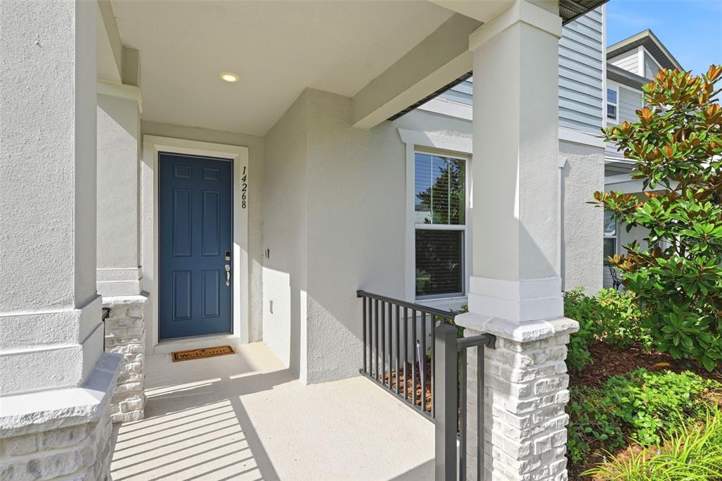 A blue front door is set within a covered porch featuring stone-based columns — 14268 BRAEMAR STREET, WINTER GARDEN, FL