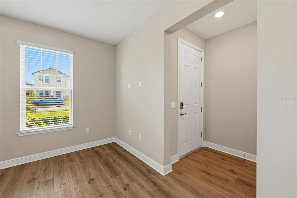 A room with wood-look flooring, a window with blinds, and a white door — 14268 BRAEMAR STREET, WINTER GARDEN, FL