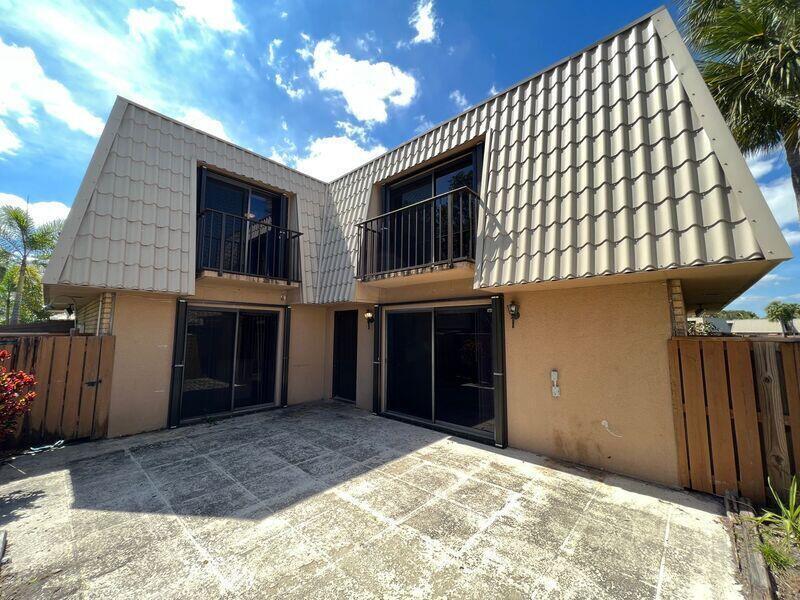 The exterior of a two-story townhouse features a concrete patio, balconies, and a mansard roof — 5714 57th Way, West Palm Beach FL 33409, WEST PALM BEACH, FL