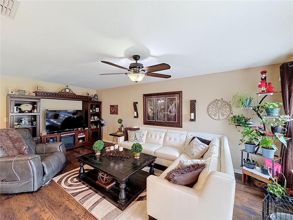 A living room features a white sectional sofa, a dark wood coffee table, and a television — 6420 WINDSOR LAKE CIRCLE, SANFORD, FL