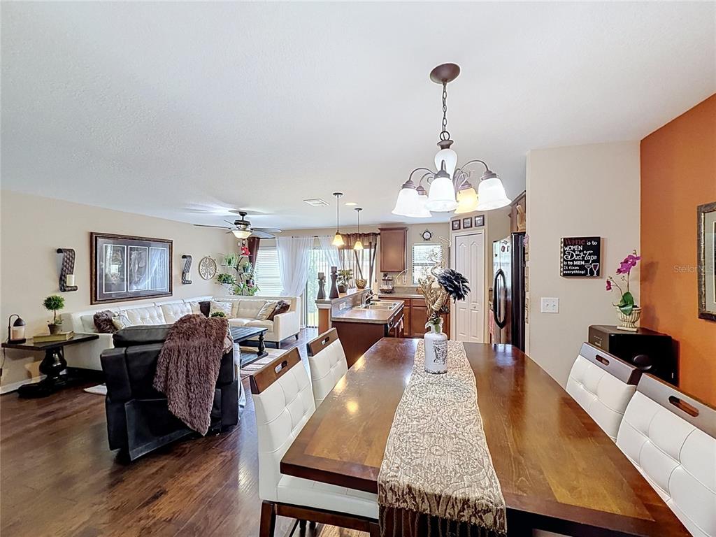 An open-concept dining room and living area with dark wood floors and white furniture — 6420 WINDSOR LAKE CIRCLE, SANFORD, FL
