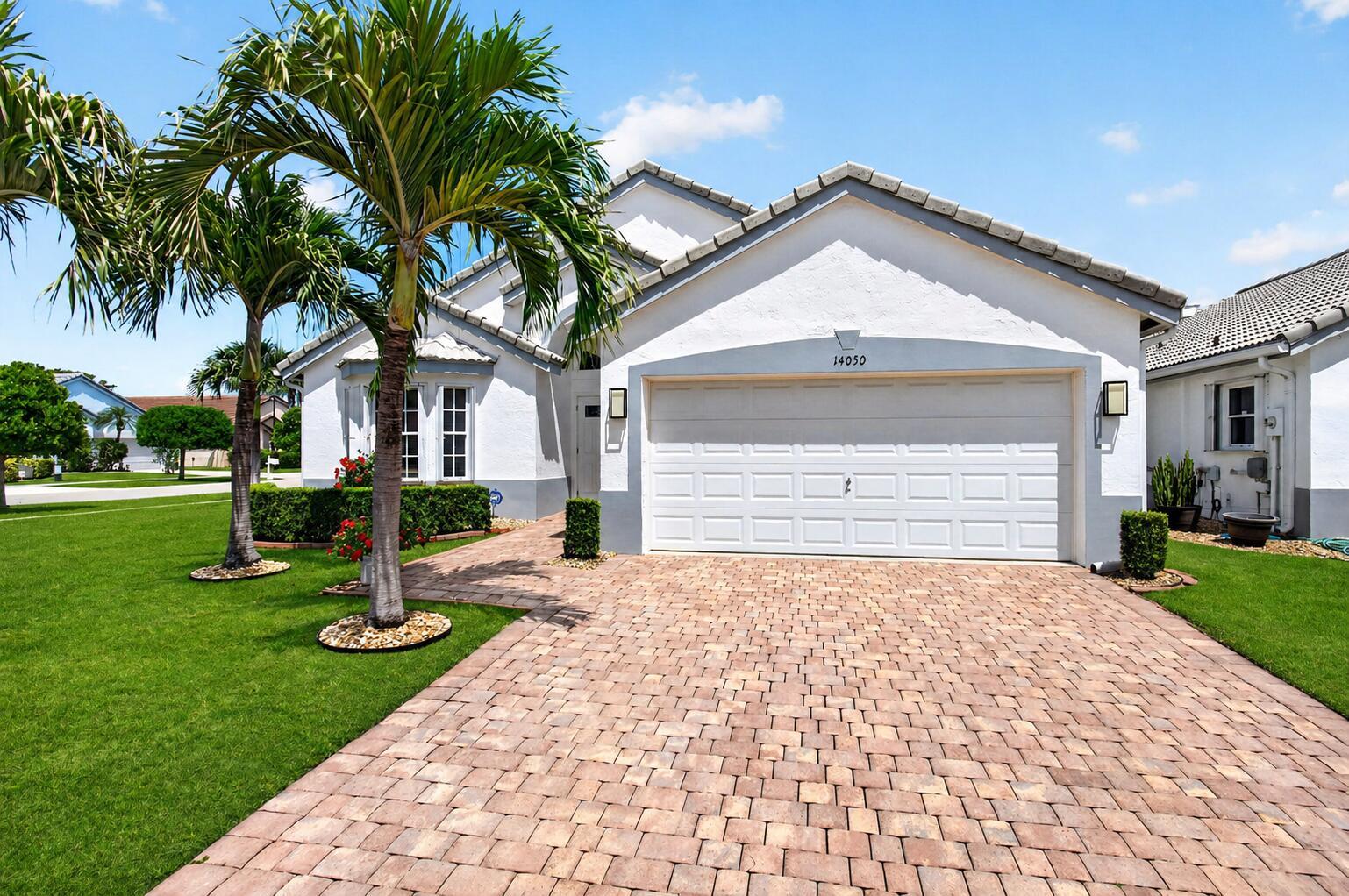 A white house with a paved driveway, palm trees, and a two-car garage — 14050 Fair Isle Drive, Delray Beach FL 33446, DELRAY BEACH, FL