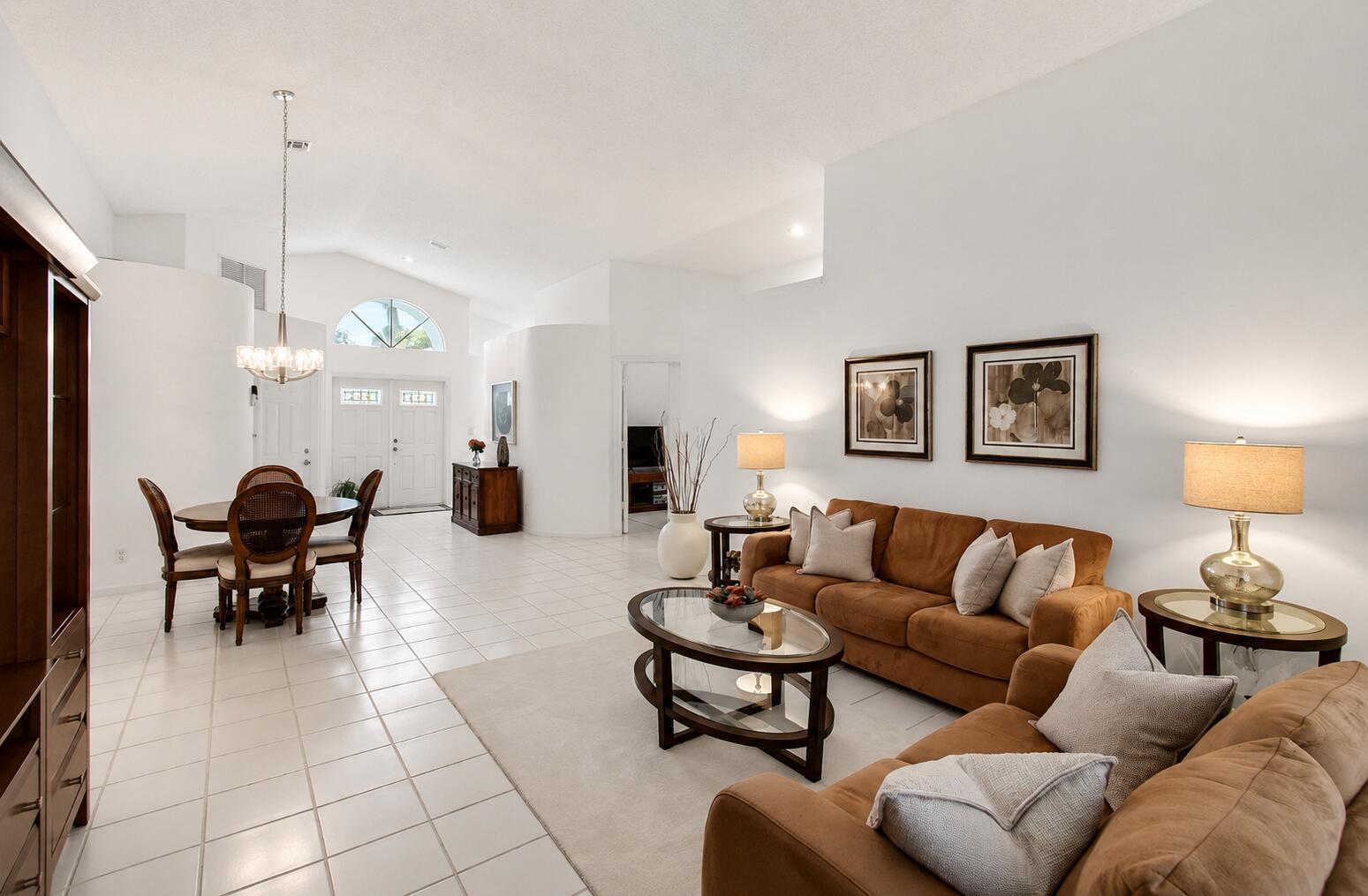 A bright living and dining area with white tile floors, vaulted ceilings, and brown furniture — 14050 Fair Isle Drive, Delray Beach FL 33446, DELRAY BEACH, FL