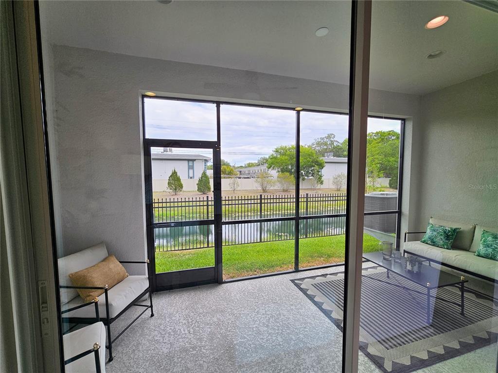 A screened-in patio features a concrete floor, outdoor furniture, and a view of a pond — 7765 93RD STREET N, SEMINOLE, FL