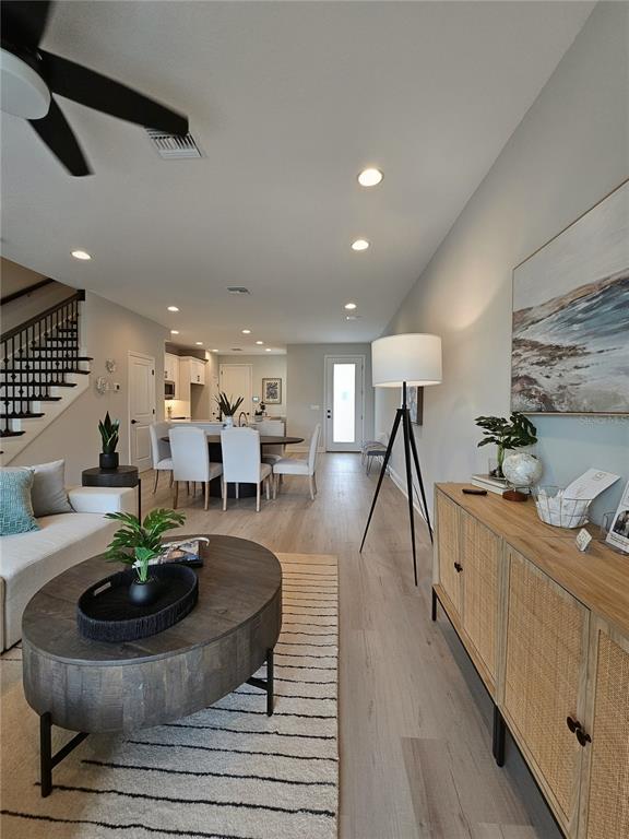 This open-concept living and dining area features light wood flooring, a modern staircase, and recessed lighting — 7765 93RD STREET N, SEMINOLE, FL