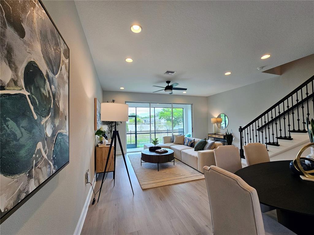 A modern living room features a sectional sofa, a tripod floor lamp, and a staircase — 7765 93RD STREET N, SEMINOLE, FL
