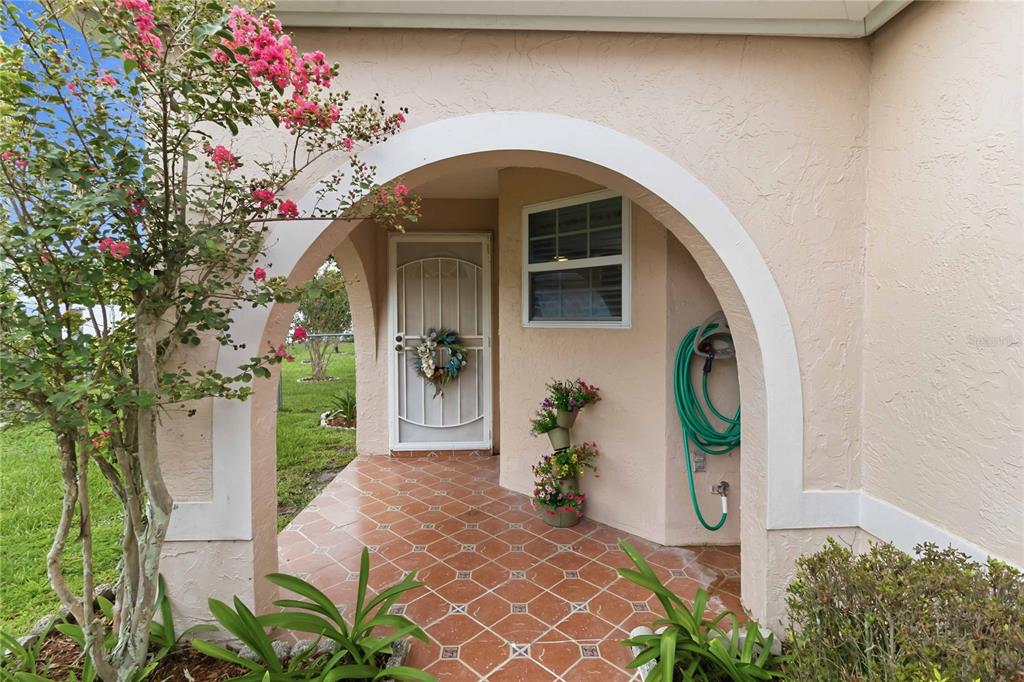 A covered entryway features a tiled porch, an arched opening, and a white screen door — 2918 CANOE CIRCLE, ST CLOUD, FL