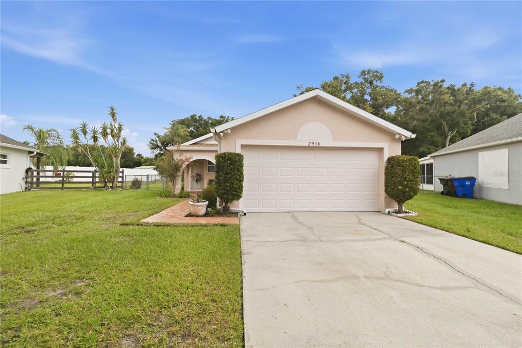 A single-story house with a beige stucco exterior, a two-car garage, and a concrete driveway — 2918 CANOE CIRCLE, ST CLOUD, FL