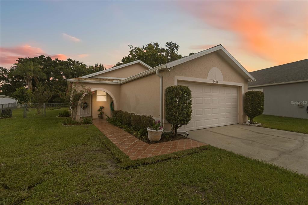 A single-story house with a beige stucco exterior, a two-car garage, and a tiled walkway — 2918 CANOE CIRCLE, ST CLOUD, FL