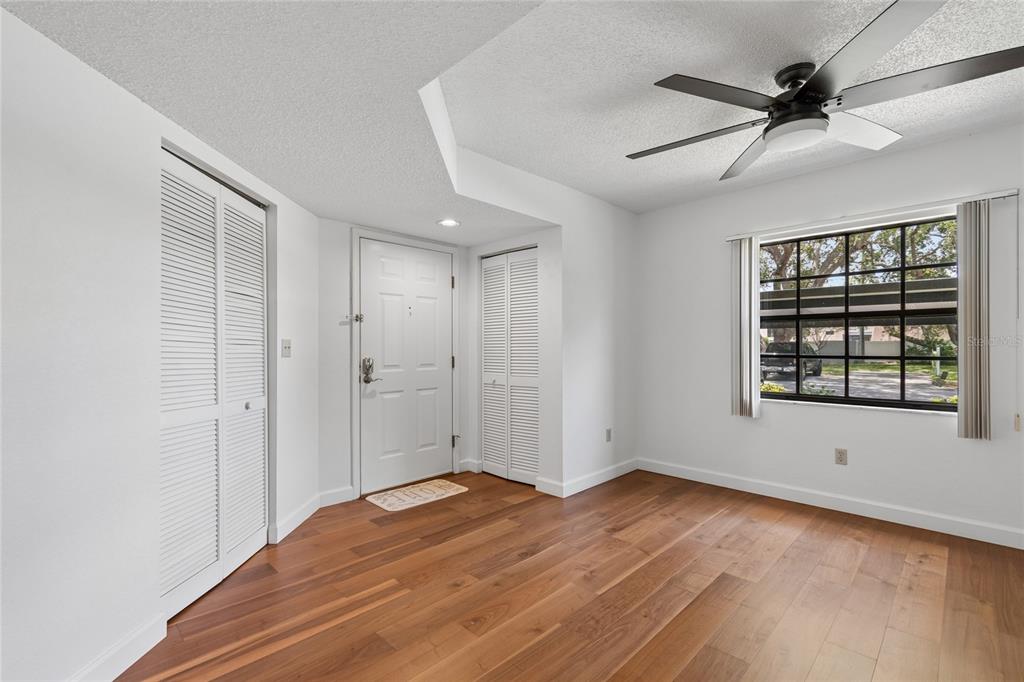 An entryway with wood flooring, white walls, two louvered closets, and a ceiling fan — 11800 PARK BLVD UNIT 401, SEMINOLE, FL