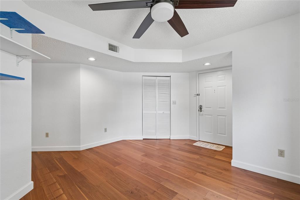 An empty room with white walls, wood flooring, a ceiling fan, and a white door — 11800 PARK BLVD UNIT 401, SEMINOLE, FL