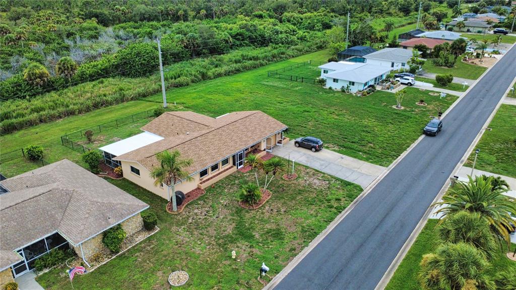 An aerial view shows a suburban neighborhood with single-story houses, driveways, and surrounding green space — 27 ANNAPOLIS LANE, ROTONDA WEST, FL