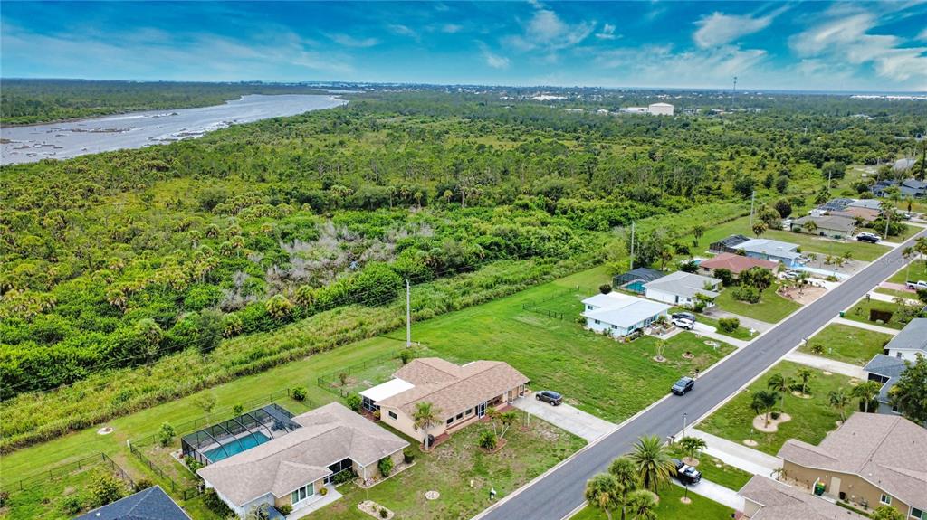 An aerial view shows suburban houses along a road bordering a large area of dense vegetation — 27 ANNAPOLIS LANE, ROTONDA WEST, FL