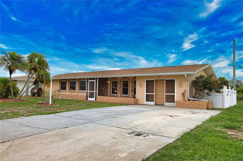 A single-story house with a tan exterior, a concrete driveway, and palm trees — 27 ANNAPOLIS LANE, ROTONDA WEST, FL