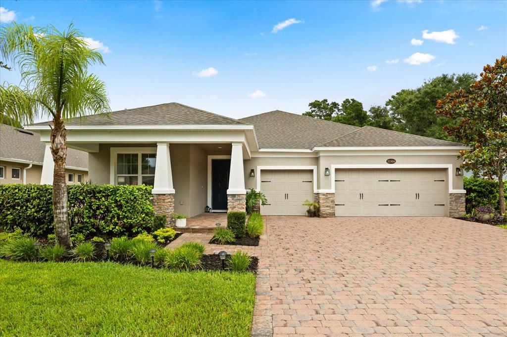 A single-story house with a stone-accented porch, a paver driveway, and a three-car garage — 31924 GEOFF WAY, SORRENTO, FL