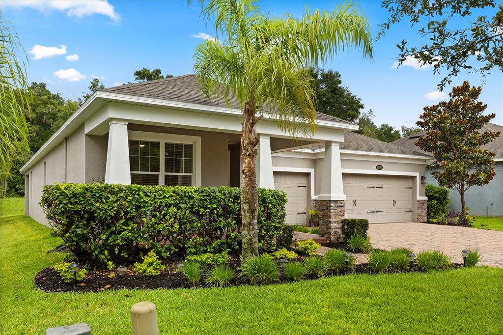 A single-story house with a stone-accented garage, a covered front porch, and a manicured hedge — 31924 GEOFF WAY, SORRENTO, FL