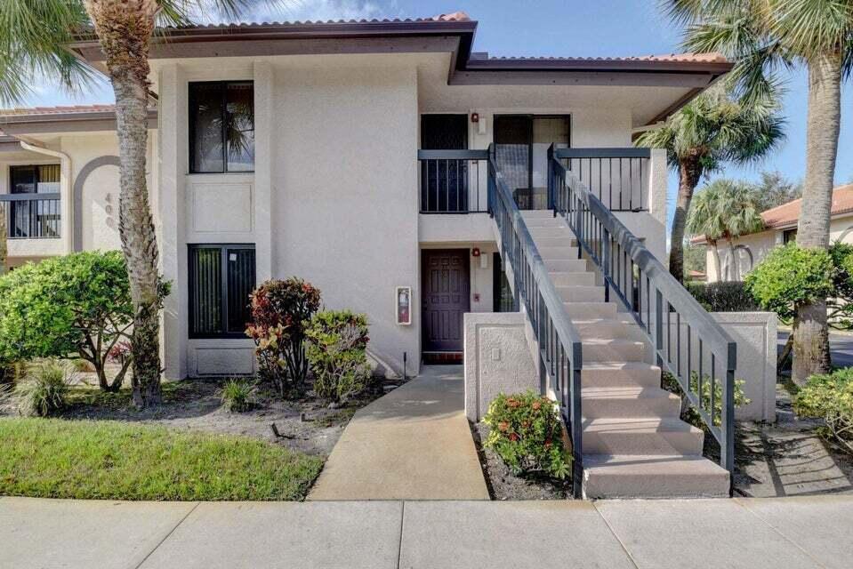 A two-story stucco apartment building with an exterior staircase leading to an upper balcony — 400 Club Circle # 101, Boca Raton FL 33487, BOCA RATON, FL