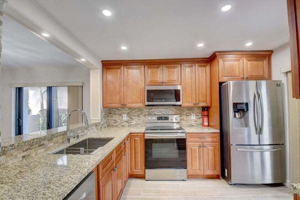 A kitchen featuring wood cabinets, granite countertops, stainless steel appliances, and a tiled backsplash — 400 Club Circle # 101, Boca Raton FL 33487, BOCA RATON, FL