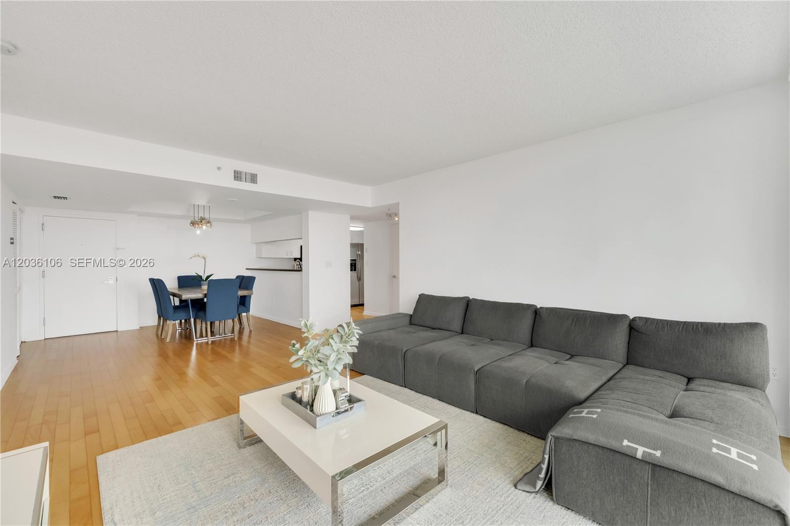 A living room features a grey sectional sofa, a white coffee table, and a dining area — 650 West Ave # 704, Miami Beach FL 33139, MIAMI BEACH, FL