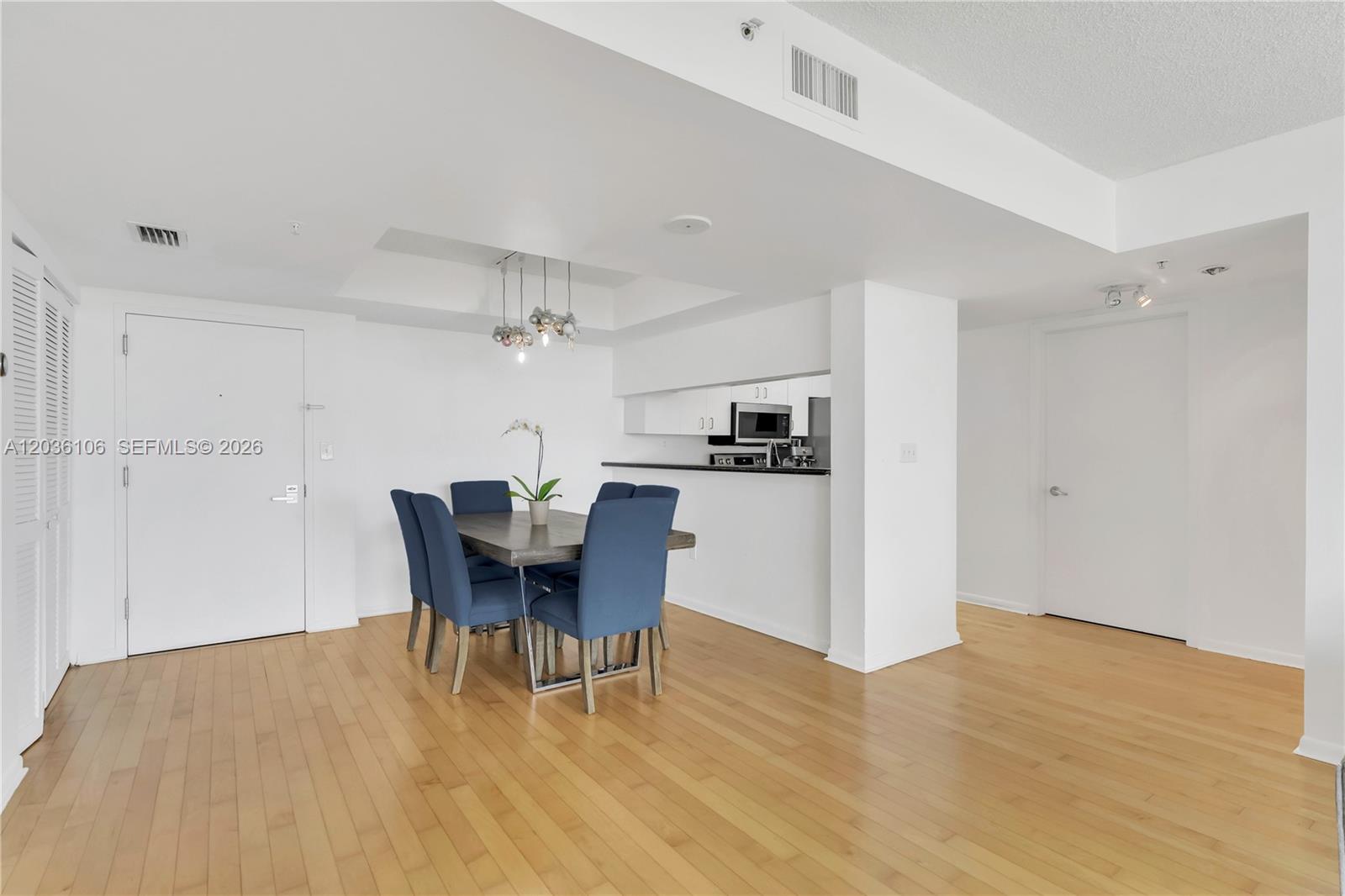 A dining area with a wooden table and blue chairs sits adjacent to a kitchen — 650 West Ave # 704, Miami Beach FL 33139, MIAMI BEACH, FL