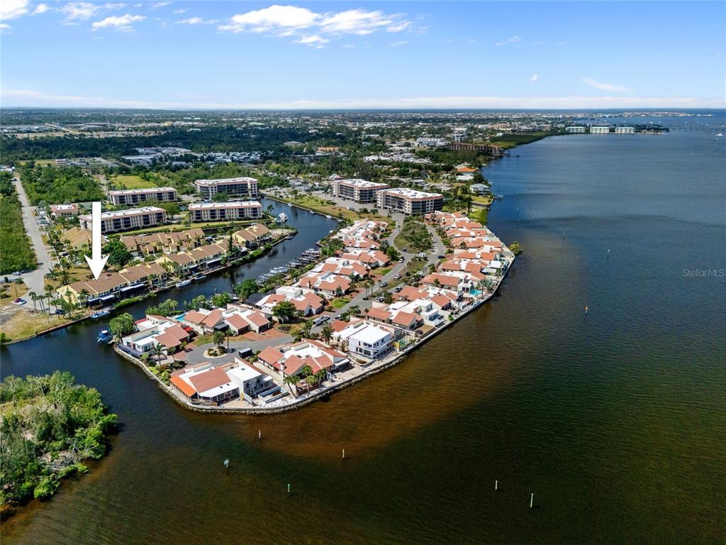 An aerial view shows a waterfront residential complex with townhomes, boat slips, and surrounding vegetation — 25188 MARION AVENUE UNIT 1038, PUNTA GORDA, FL