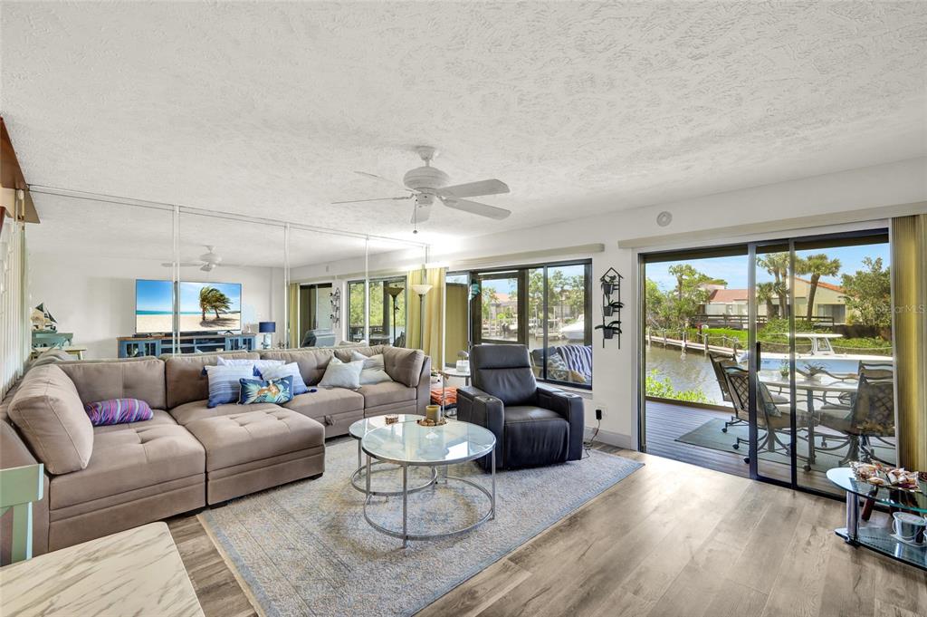 A living room with a sectional sofa, mirrored wall, and sliding glass doors to a deck — 25188 MARION AVENUE UNIT 1038, PUNTA GORDA, FL