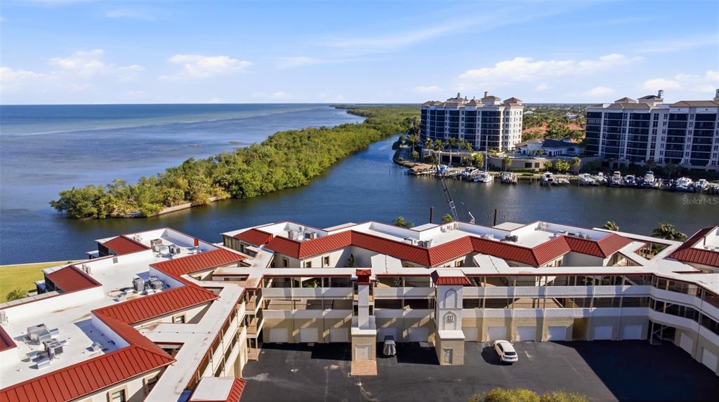 An aerial view shows a multi-story residential complex with red roofs near a coastal waterway — 3270 SOUTHSHORE DRIVE UNIT 72A, PUNTA GORDA, FL