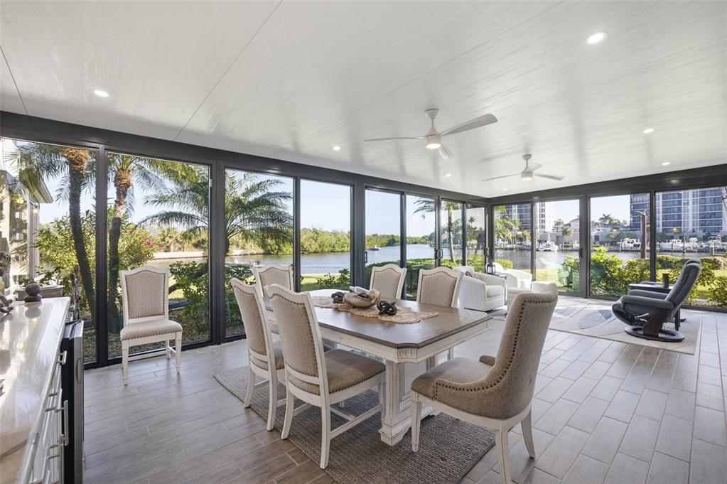 A sunroom with a dining set, tile flooring, and floor-to-ceiling windows overlooking a waterway — 3270 SOUTHSHORE DRIVE UNIT 72A, PUNTA GORDA, FL