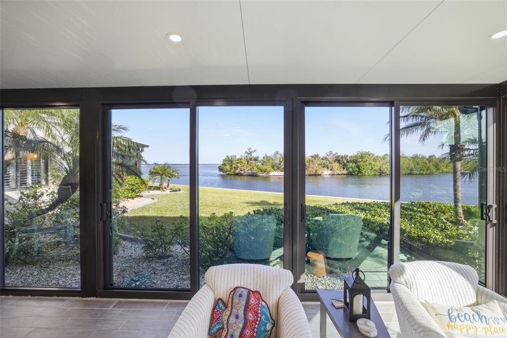 A sunroom with tile floors features large sliding glass doors overlooking a waterfront backyard — 3270 SOUTHSHORE DRIVE UNIT 72A, PUNTA GORDA, FL