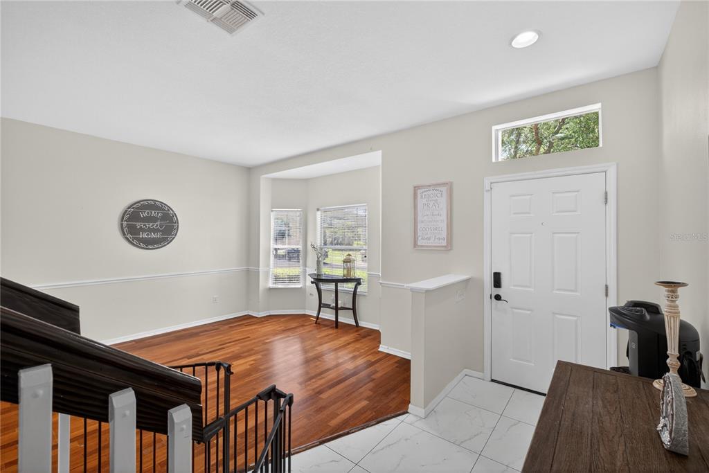 An entryway with white tile floors leads to a living area with hardwood flooring — 14903 YORKSHIRE RUN DRIVE, ORLANDO, FL