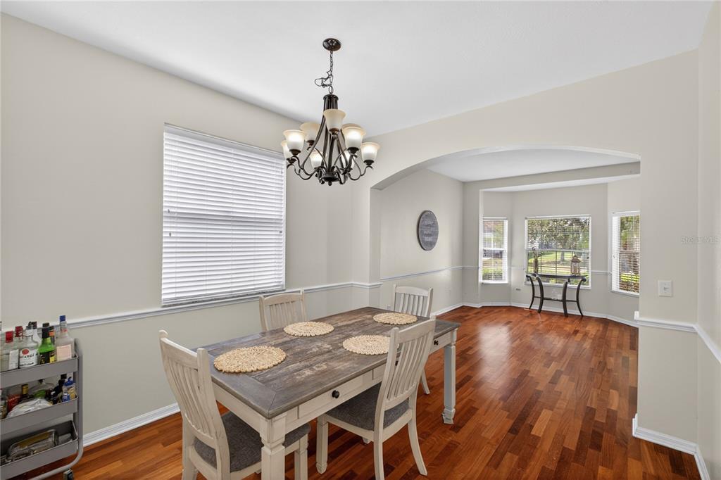 A dining room with hardwood floors, a wooden table, and a chandelier under an archway — 14903 YORKSHIRE RUN DRIVE, ORLANDO, FL