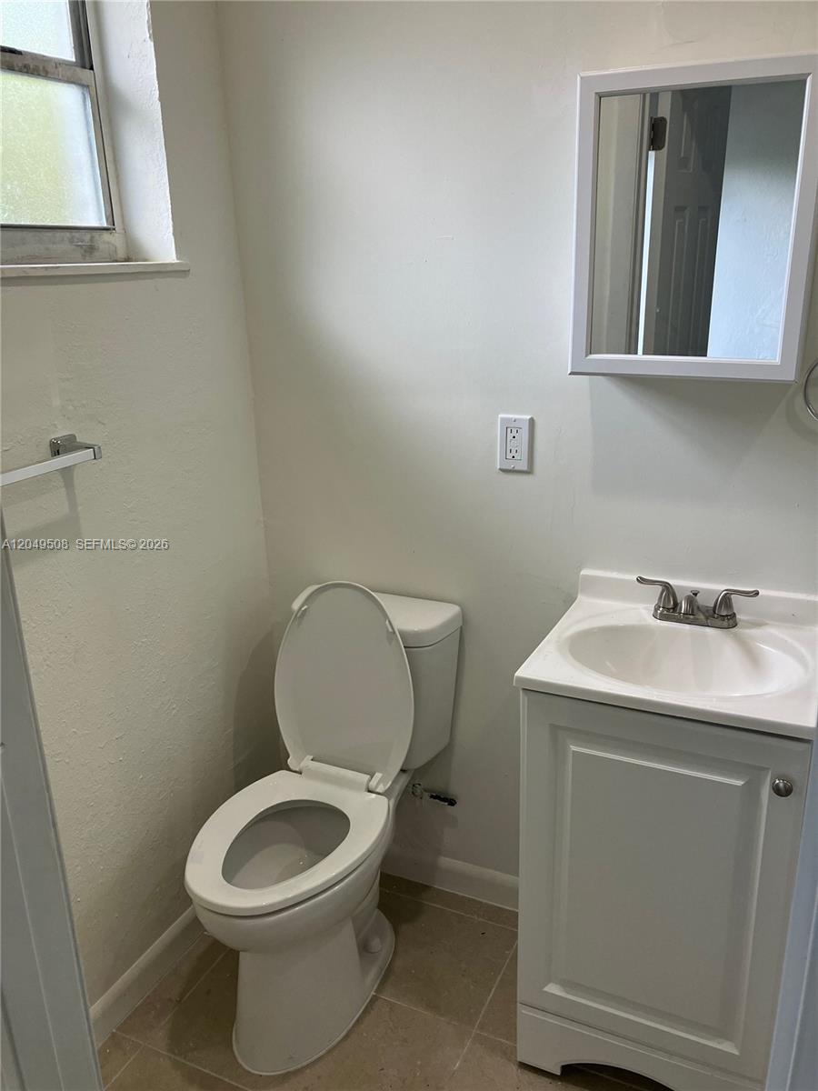 A small bathroom features a white toilet, a vanity with a sink, and a mirror — 467 NW 8th St # 4, Miami FL 33136, MIAMI, FL