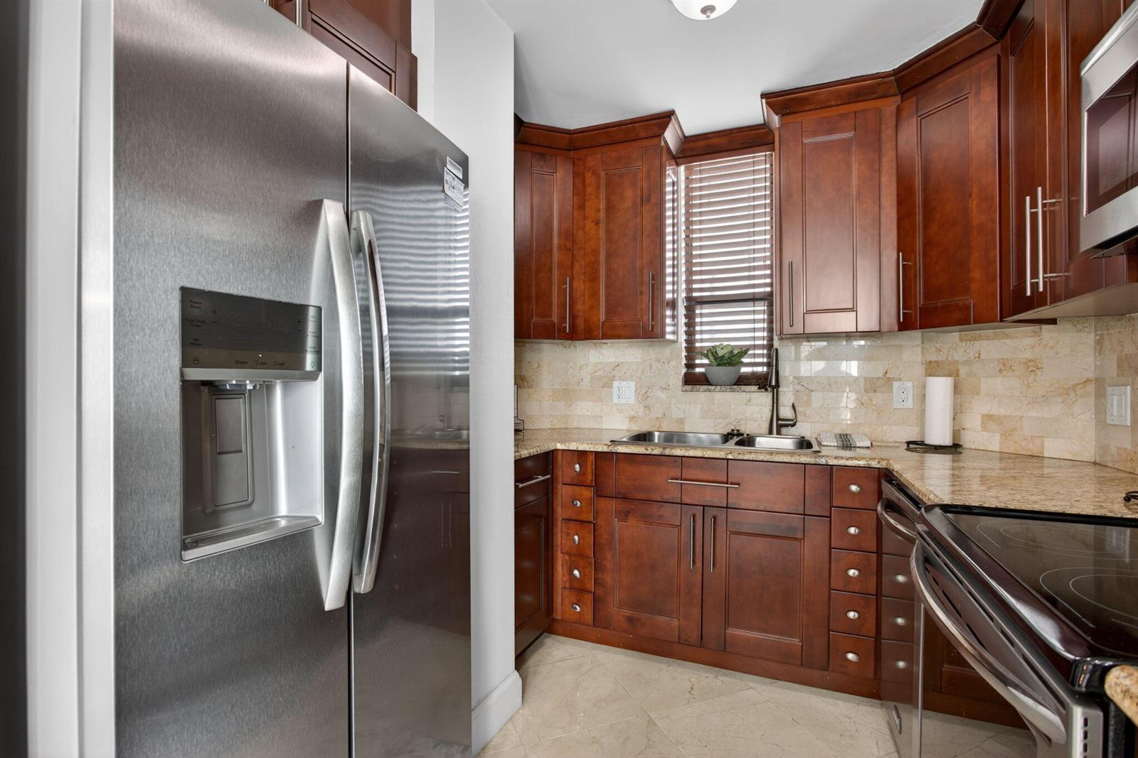 A kitchen features stainless steel appliances, dark wood cabinetry, granite countertops, and a stone backsplash — 1000 S Ocean Boulevard # 5j, Pompano Beach FL 33062, POMPANO BEACH, FL