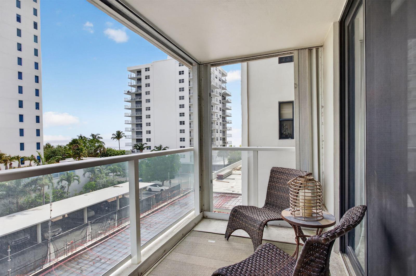 A balcony with wicker chairs and a small table overlooks a construction site and buildings — 1000 S Ocean Boulevard # 5j, Pompano Beach FL 33062, POMPANO BEACH, FL