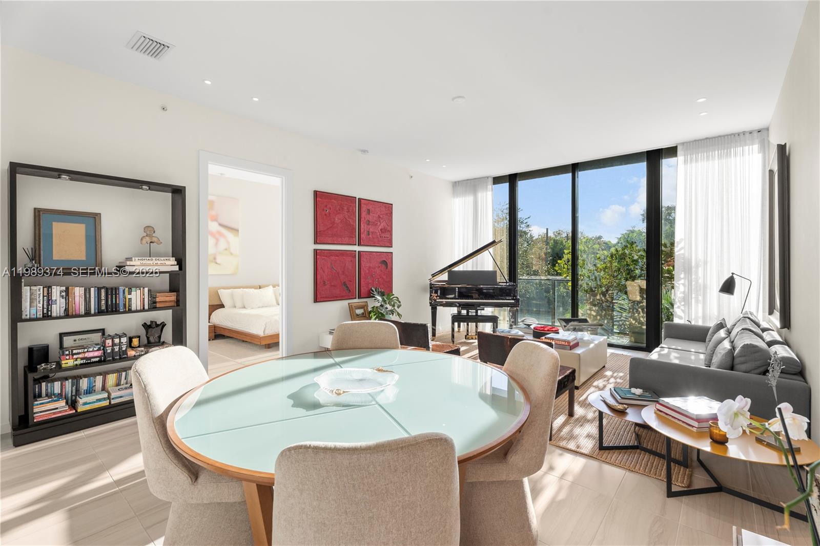 A modern living and dining area features a glass-topped table, grand piano, and floor-to-ceiling windows — 3156 SW 27th Ave # 202, Miami FL 33133, MIAMI, FL