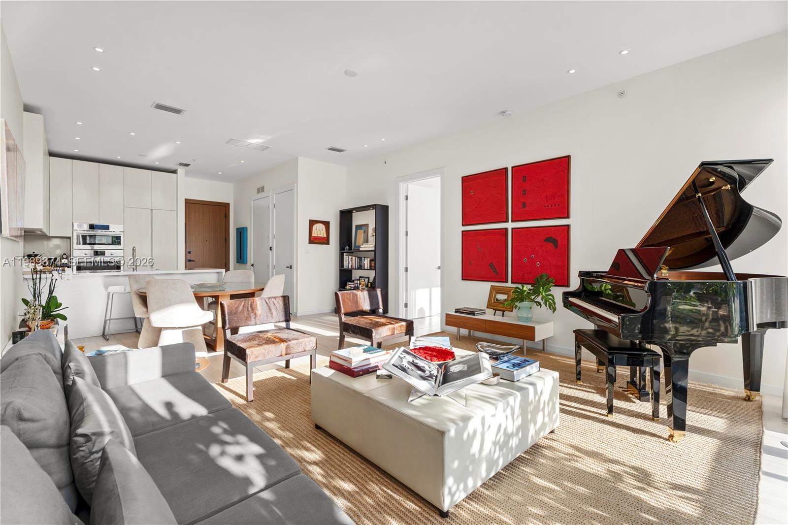 A modern living room features a grand piano, gray sofa, and four red wall art pieces — 3156 SW 27th Ave # 202, Miami FL 33133, MIAMI, FL