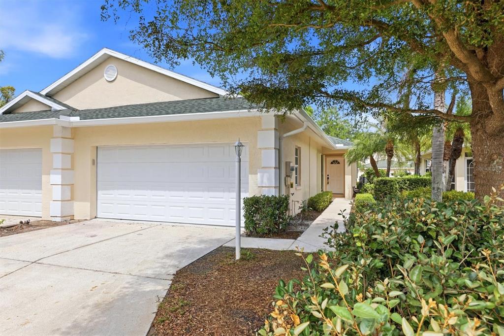 A light-colored duplex home features a two-car garage, a concrete driveway, and landscaping — 503 AUBURN COVE CIRCLE, VENICE, FL
